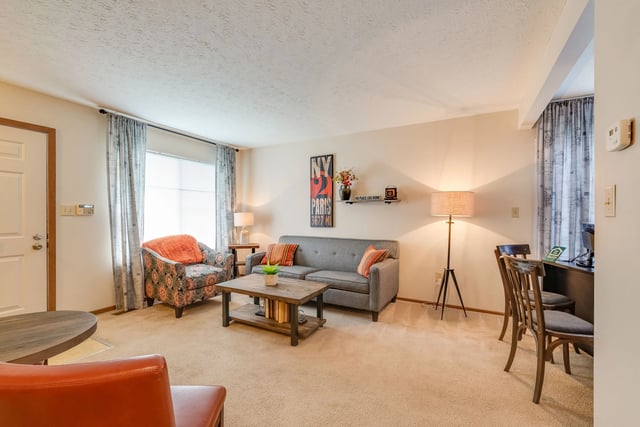 Living room with a gray sofa, patterned armchair, coffee table, and dining area.