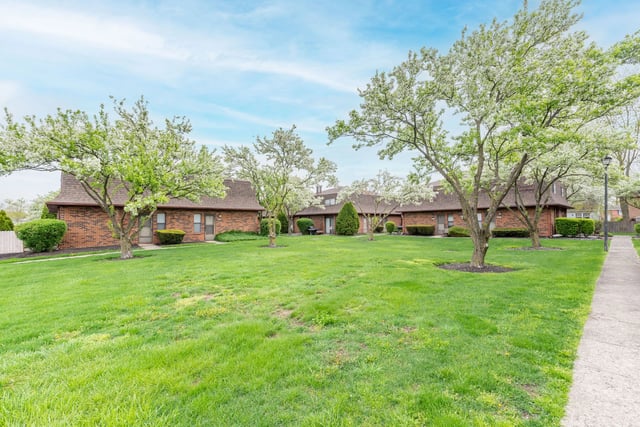 Brick apartment buildings surrounded by lush green grass and blooming trees.