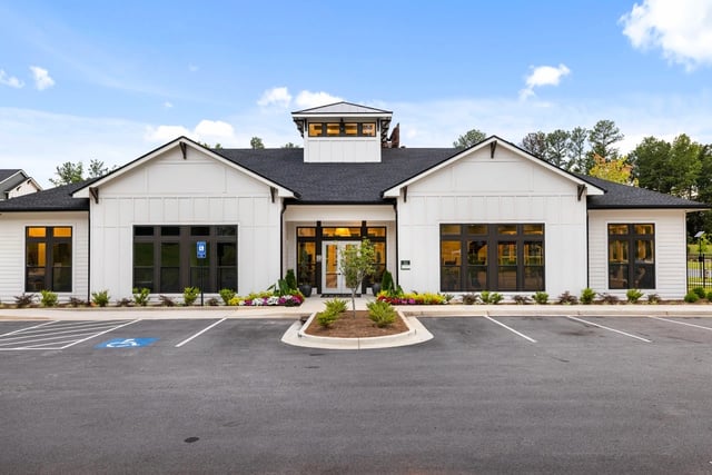 Exterior of a modern white apartment building with large windows and a welcoming entrance.