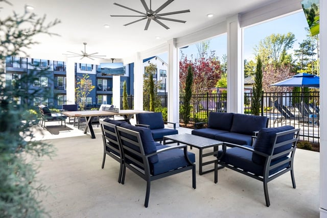 Outdoor lounge area with seating and a table, overlooking the pool.