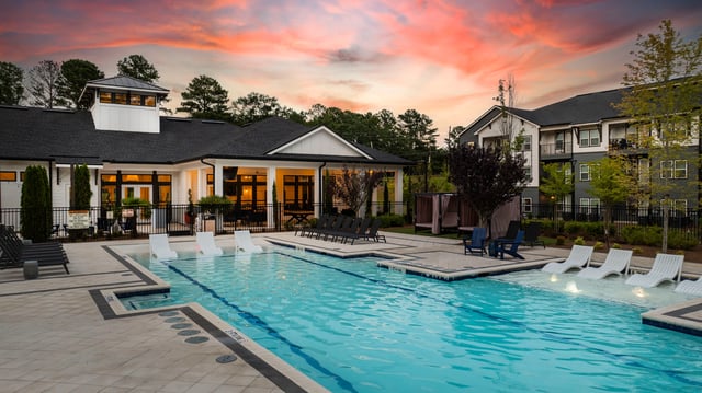 Modern swimming pool with lounge chairs and cabanas at sunset.