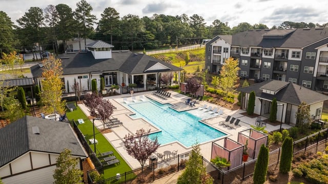 Aerial view of a luxury apartment complex with a large swimming pool and surrounding lounge area at NOVO Stockbridge in Stockbridge, GA.