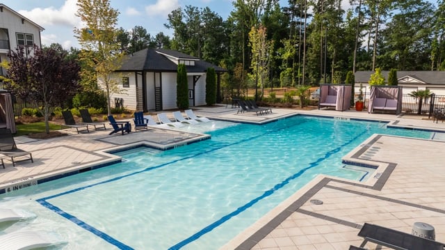 Luxury swimming pool with lounge chairs and cabanas.