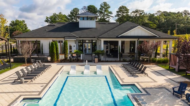Resort-style swimming pool and lounge chairs with clubhouse in background