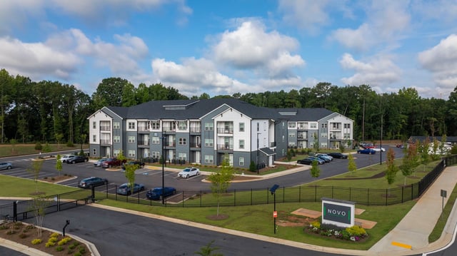 Modern apartment building exterior with parking lot and NOVO signage.