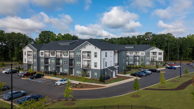 Exterior of apartment buildings with a parking lot in front.