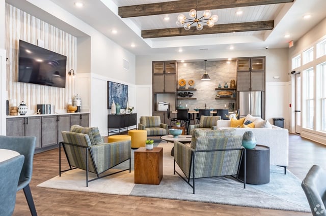 Modern communal lounge with comfortable seating, large television, and a wet bar.