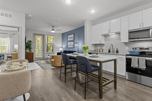 Modern kitchen and living area with island seating and dining table.