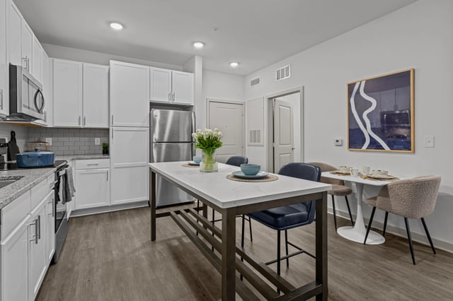 Modern kitchen with white cabinets, stainless steel appliances, and a large island.