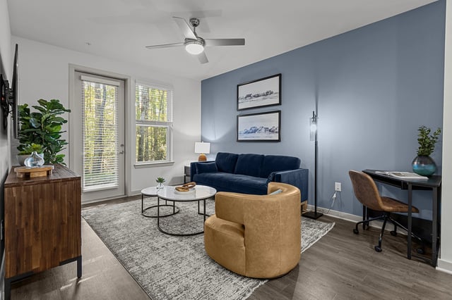 Living room with a blue couch, leather accent chair, coffee table, and desk.