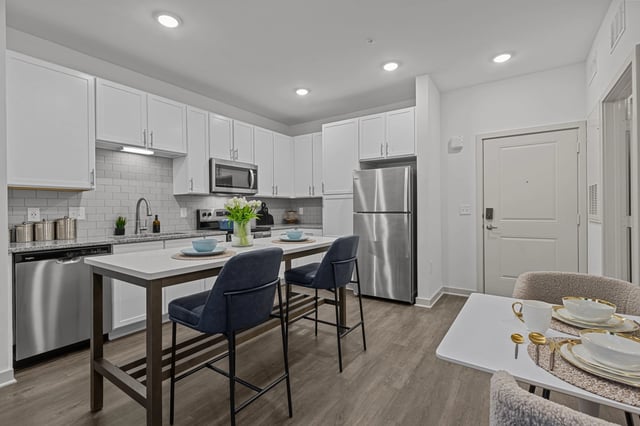 Modern kitchen with white cabinets, stainless steel appliances, and a large island with seating.