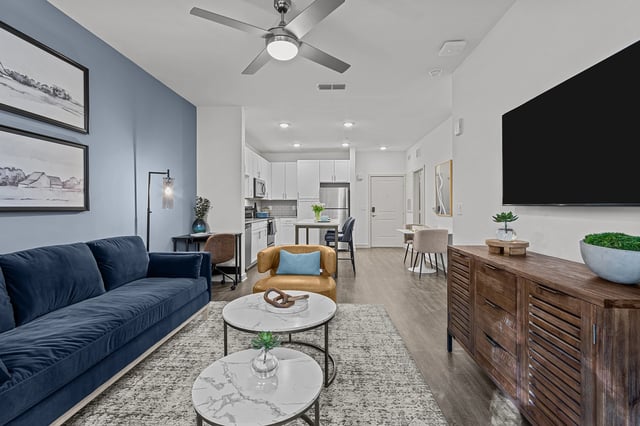 Modern living room and kitchen area with a blue sofa, accent chair, and island.