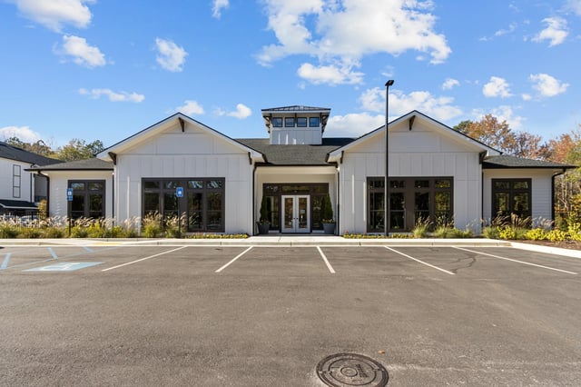 Exterior of a modern multifamily building with white siding and large dark-framed windows.