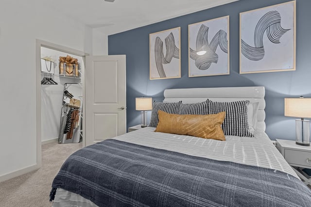 Bedroom with a king-size bed, navy blue accent wall, and walk-in closet.