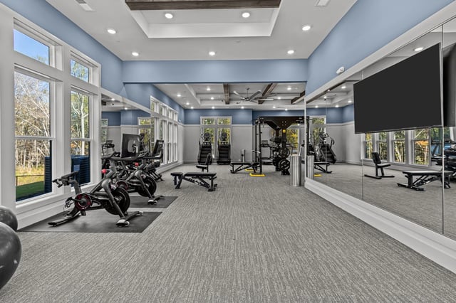 Modern fitness center with cardio equipment, weights, and mirrors.