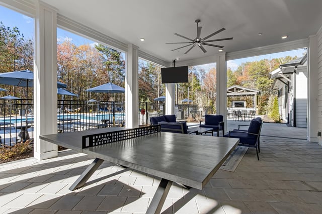 Outdoor covered patio with ping pong table, seating, and a view of the pool.