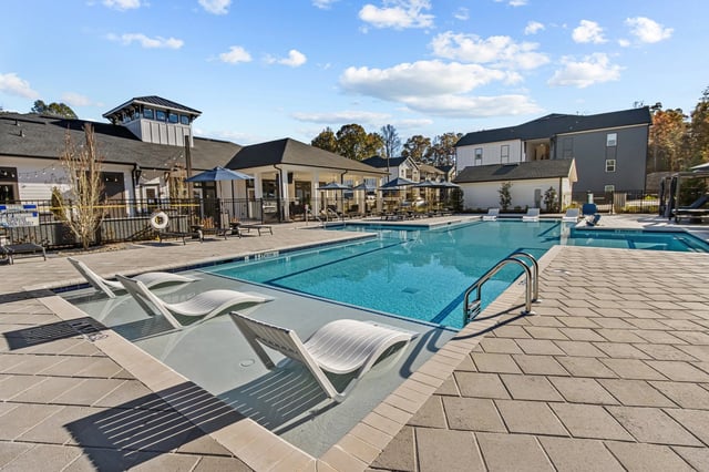Modern swimming pool with lounge chairs and a cabana area.