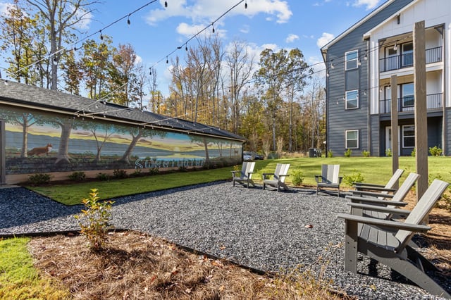 Outdoor seating area with Adirondack chairs and a mural on a building.