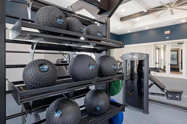 Gym equipment including slam balls and weight bench.