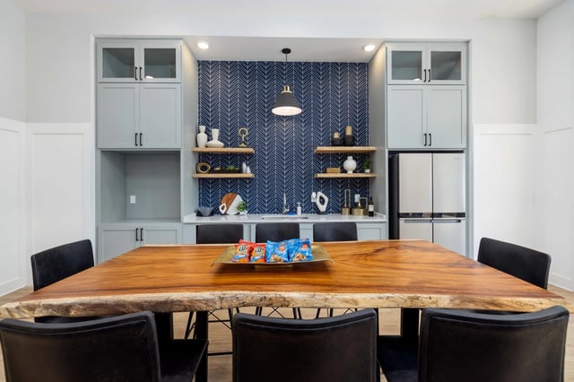 Community lounge area with a live-edge wood table, comfortable seating, and a modern kitchen backsplash.