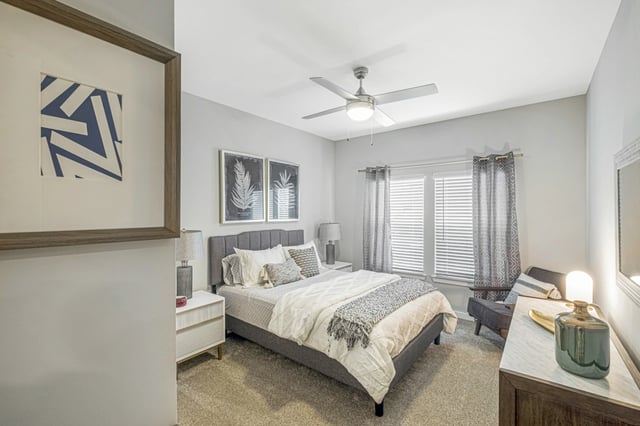 Bedroom with a queen-size bed, nightstand, and armchair.