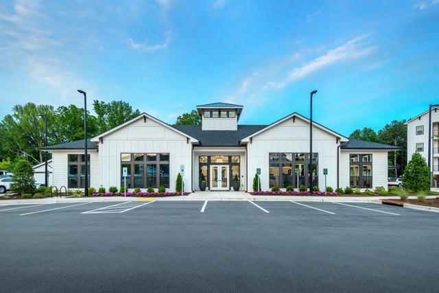 Exterior view of a modern multifamily property's clubhouse building, featuring white siding and large windows.