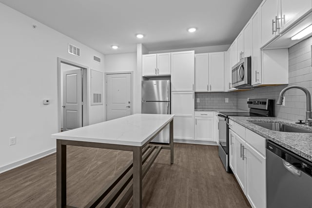 Modern kitchen with white cabinets, stainless steel appliances, large island, and granite countertops.