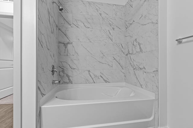 Modern bathroom with marble tile shower and white bathtub.