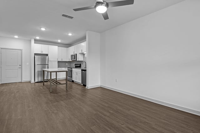 Modern kitchen and living area in an apartment with stainless steel appliances and island.