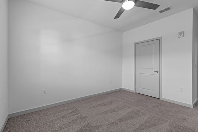 Empty bedroom with neutral carpet and a ceiling fan.