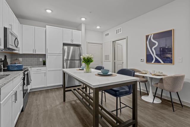 Modern kitchen with stainless steel appliances, white cabinets, and a large island.