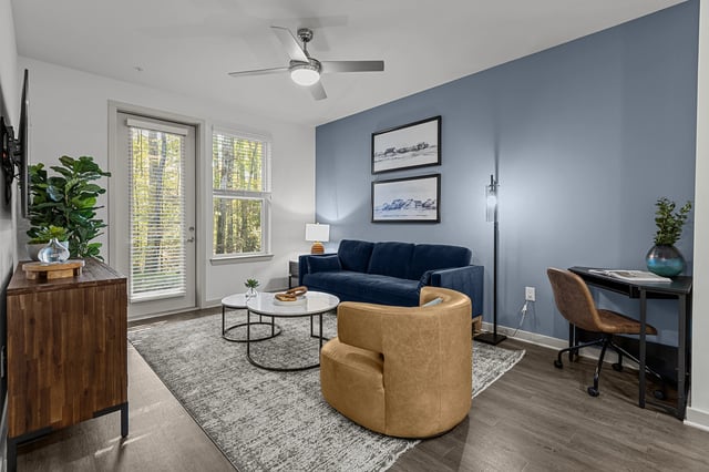 Living room with blue sofa, tan accent chair, coffee table, and desk.