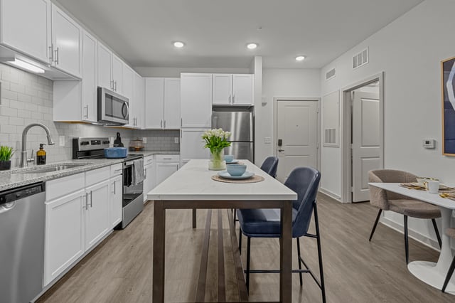 Modern kitchen with white cabinets, granite countertops, stainless steel appliances, and an island with seating.