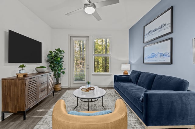 Stylish living room with blue sofa, tan accent chair, and entertainment center.