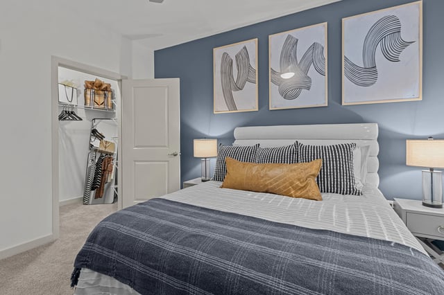 Interior of a bedroom with a queen-size bed, a closet, and modern artwork.