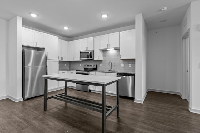 Modern kitchen with stainless steel appliances, white cabinetry, and a large island.