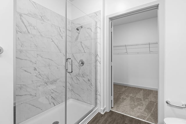 Modern bathroom with a walk-in shower with marble tile and a nearby walk-in closet.