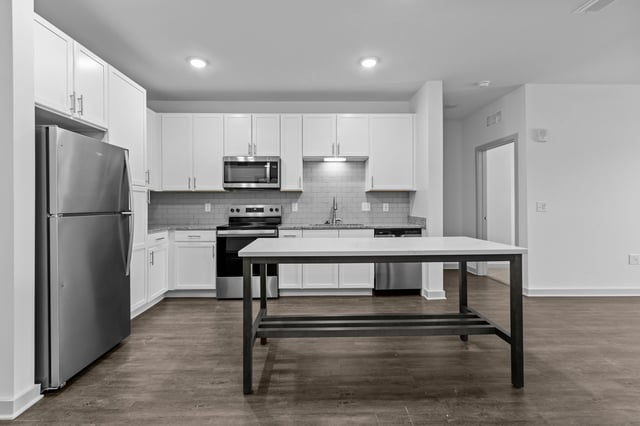 Modern kitchen with white cabinets, stainless steel appliances, and a large island.
