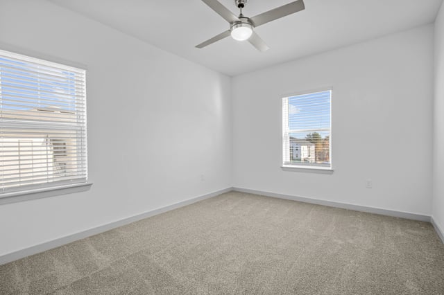 Empty bedroom with a ceiling fan and two windows.