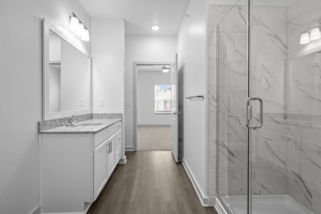 Modern bathroom with vanity, granite countertop, and glass-enclosed shower.