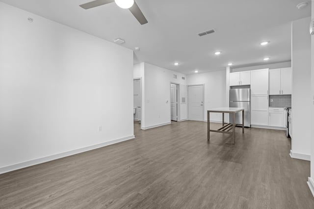 Open concept living and kitchen area with stainless steel appliances and a ceiling fan.