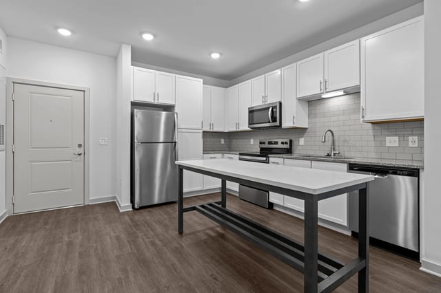 Modern kitchen with stainless steel appliances, white cabinets, and a large island.