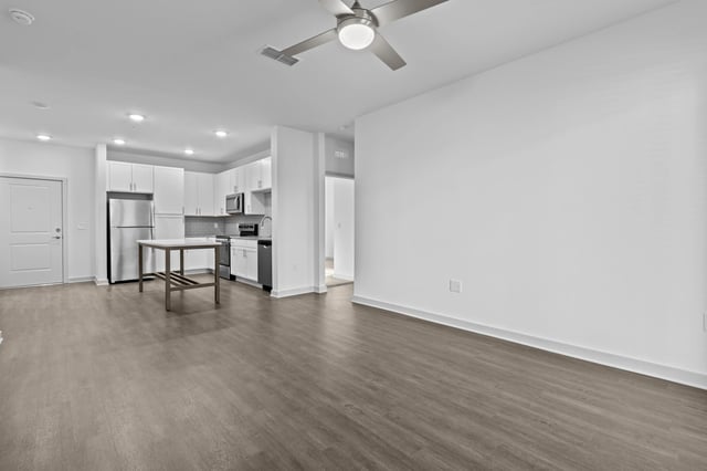 Open-concept living space with a modern kitchen featuring white cabinetry and stainless steel appliances.