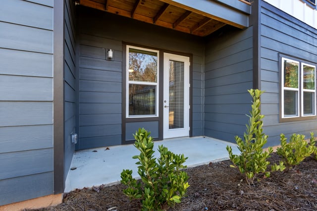 Ground floor patio entrance with gray siding and a white door.