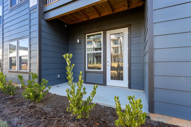 Exterior view of a building entrance with a door and window, surrounded by landscaping.