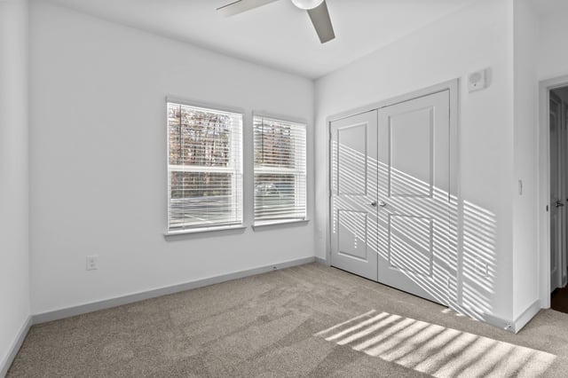Bedroom with two windows, a closet, and a ceiling fan.