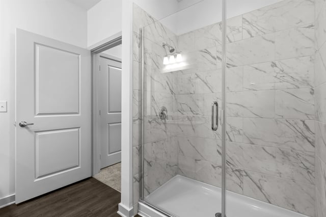Modern walk-in shower with marble tile and glass door.