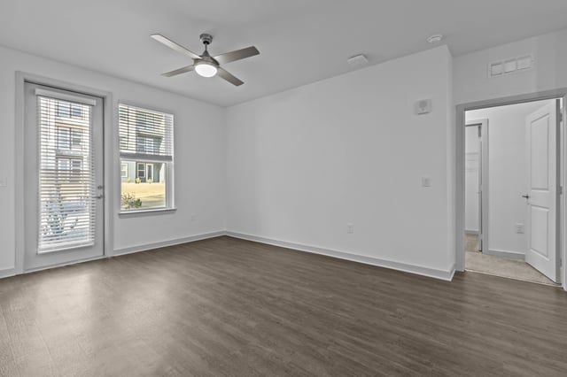 Spacious living area with a ceiling fan and large windows offering views of the exterior buildings.