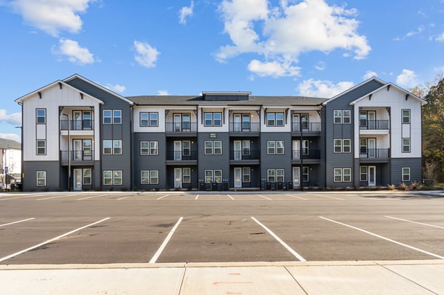 Exterior of a modern apartment building with dark gray and white siding and balconies.