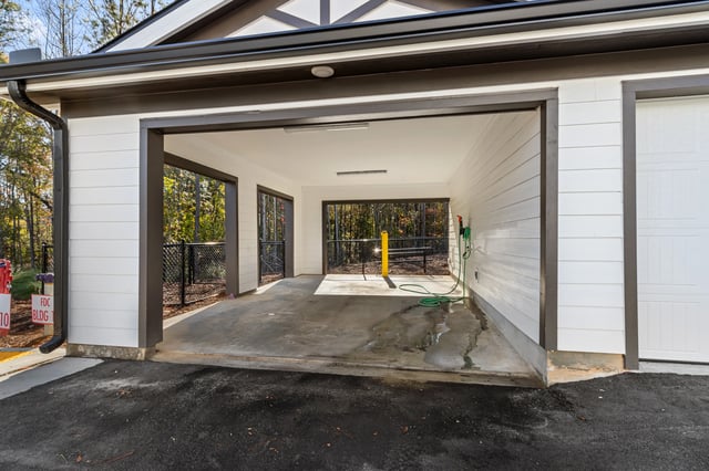 Open garage bay with hose and lush trees in the background.